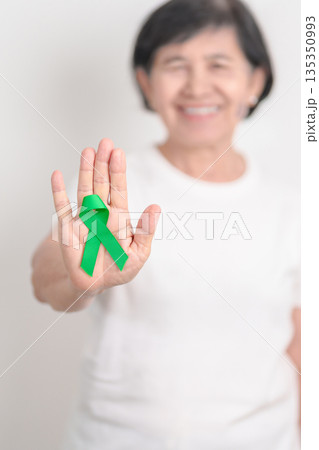 Elderly with Green Ribbon for concept of March world Bipolar disorder day, Cerebral Palsy Awareness month, kidney disease Cancer and Traumatic Brain Injury, TBI. Healthcare and world cancer day Elderly with Green Ribbon for concept of March world Bipolar disorder day, Cerebral Palsy Awareness month, kidney disease Cancer and Traumatic Brain Injury, TBI. Healthcare and world cancer day 135350993