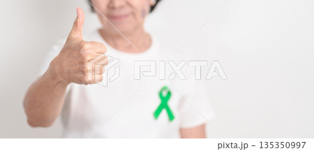 Elderly with Green Ribbon for concept of March world Bipolar disorder day, Cerebral Palsy Awareness month, kidney disease Cancer and Traumatic Brain Injury, TBI. Healthcare and world cancer day 135350997