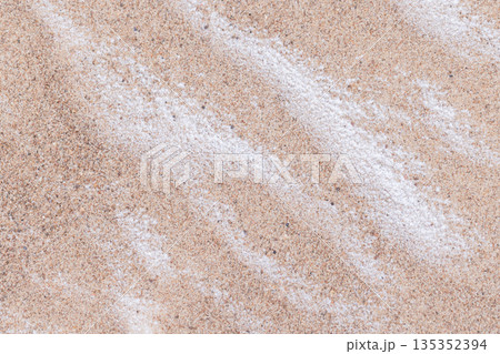 Frozen sand pattern partly covered with snow on a winter beach. Baltic Sea coast 135352394