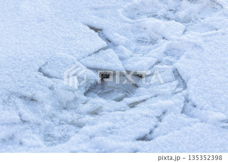 A tranquil winter close-up showing broken ice shards buried under snow 135352398