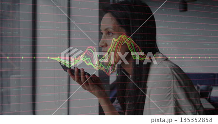 Issuing voice command woman holding smartphone by window at home office, with analytics overlay 135352858