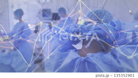 Surgical team member in blue scrubs adjusting mask and cap in operating room, with data graphs 135352901