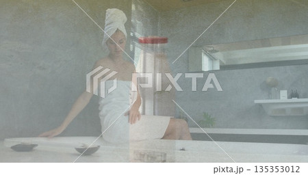 Sitting spa guest adjusting towel turban on head at spa bathroom marble bench, with shallow bowls Sitting spa guest adjusting towel turban on head at spa bathroom marble bench, with shallow bowls 135353012