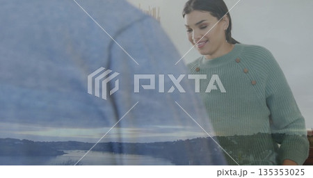 Mid adult woman in mint sweater smiling in modern room, with glass panel and reed diffuser 135353025