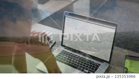 Woman coding on laptop and checking smartphone in home office with rural view, tablet, copy space 135353066