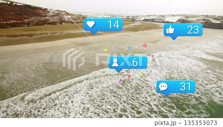 Floating blue social media icons hovering over coastal bay aerial view, with snowy hills behind 135353073