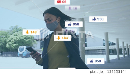 Walking woman wearing mask and blazer using smartphone in transit corridor, with notification icons Walking woman wearing mask and blazer using smartphone in transit corridor, with notification icons 135353144