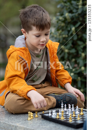 Boy playing chess outdoor. Learning strategic game. Education. Boy playing chess outdoor. Learning strategic game. Education. 135353235