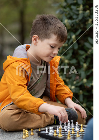 Boy playing chess outdoor. Learning strategic game. Education. Boy playing chess outdoor. Learning strategic game. Education. 135353236