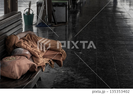 A monk is sleep on wooden chairs are waiting for trains in the area provided at Main railway station of Hua Lamphong. A monk is sleep on wooden chairs are waiting for trains in the area provided at Main railway station of Hua Lamphong. 135353402