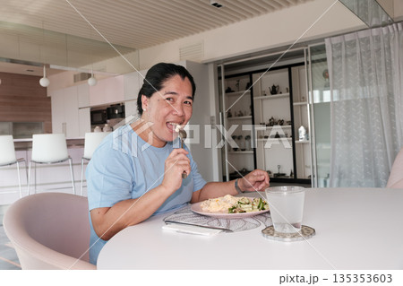 Person sits at table enjoying meal in modern dining area with simple decor during daytime Person sits at table enjoying meal in modern dining area with simple decor during daytime 135353603