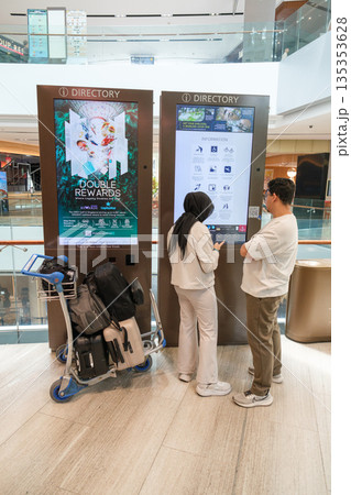 Visitors at Changi Airport interacting with digital directory in modern architecture setting Visitors at Changi Airport interacting with digital directory in modern architecture setting 135353628