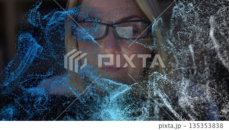 Woman wearing rectangular eyeglasses analyzing particles in dim lab, with holographic display Woman wearing rectangular eyeglasses analyzing particles in dim lab, with holographic display 135353838