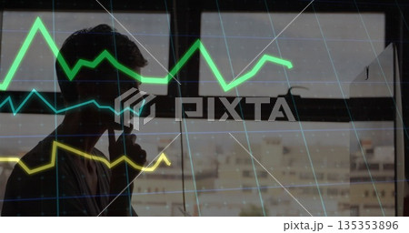 Talking man holding smartphone to ear in office by window, with colorful line graphs, copy space Talking man holding smartphone to ear in office by window, with colorful line graphs, copy space 135353896