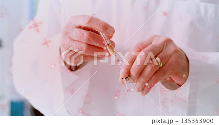 Drawing amber liquid into syringe by hands wearing lab coat in lab, with vial, wedding band Drawing amber liquid into syringe by hands wearing lab coat in lab, with vial, wedding band 135353900