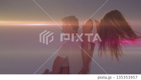 Couple wearing white tops giving piggyback ride at sunset, with pastel gradient sky 135353957