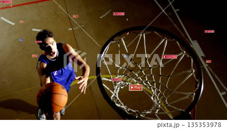 Leaping basketball player in blue jersey dunking ball at gym court, with overlay icons, copy space Leaping basketball player in blue jersey dunking ball at gym court, with overlay icons, copy space 135353978