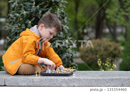 Boy playing chess outdoor. Learning strategic game. Education. Boy playing chess outdoor. Learning strategic game. Education. 135354460