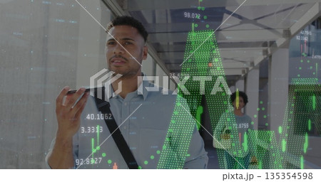 Speaking man in blue shirt talking into smartphone in corridor, with shoulder bag, market graphs 135354598