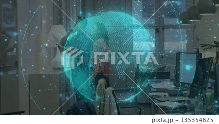 Projecting digital holographic globe overlaying modern office desks, with monitors, mugs and plants 135354625