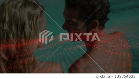 Standing couple gazing at each other in turquoise pool water, with red digital dot grid overlay 135354635