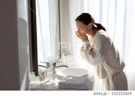 鏡を見ながら肌をチェックする日本人女性。スキンケアと美容習慣のイメージ 135355924