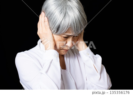 両手で耳をふさぐ白髪のシニア女性 135356176