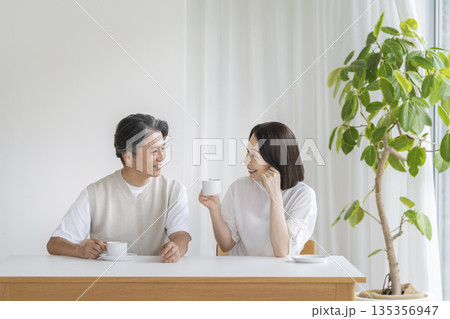 コーヒーを飲みながら話をする笑顔の50代の夫婦 135356947