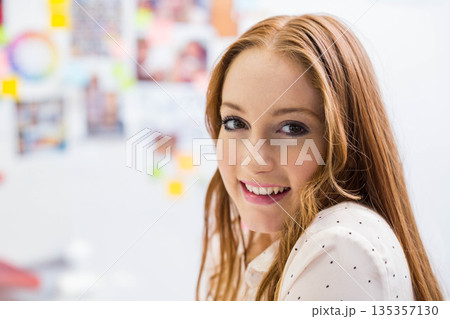 Woman in her twenties smiling in polka dot blouse beside sticky note wall pictures, copy space 135357130