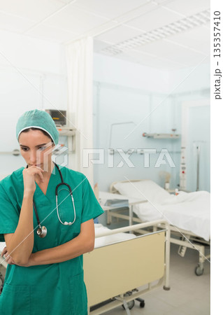 Woman standing in hospital ward wearing green scrubs and stethoscope with bed visible, copy space Woman standing in hospital ward wearing green scrubs and stethoscope with bed visible, copy space 135357410