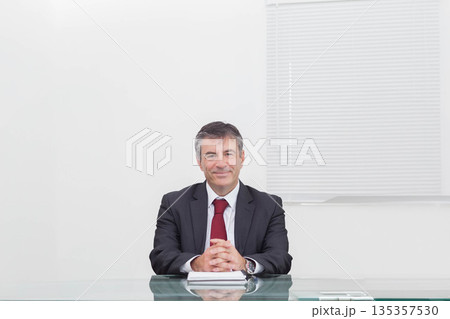 Senior man placing hands wearing wristwatch on closed notebook at transparent glass desk in office Senior man placing hands wearing wristwatch on closed notebook at transparent glass desk in office 135357530
