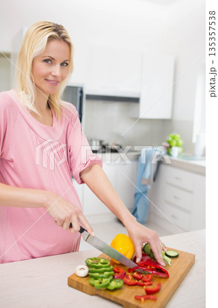 Woman slicing bell peppers and zucchini with knife on cutting board at kitchen island, copy space Woman slicing bell peppers and zucchini with knife on cutting board at kitchen island, copy space 135357538