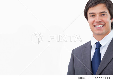 Male smiling wearing dark gray suit over white shirt and blue tie in studio, copy space Male smiling wearing dark gray suit over white shirt and blue tie in studio, copy space 135357544
