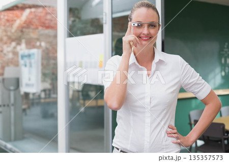 Mid adult woman standing at office wearing AR smart glasses reading sticky notes, copy space 135357573