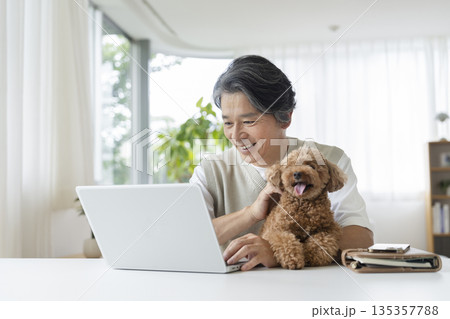 愛犬を抱えてノートパソコンで作業をする50代の男性 135357788