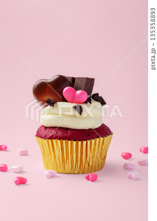 Red velvet cupcake with cream cheese frosting, decorated with heart chocolate on pink background, valentines day and celebrating love concept Red velvet cupcake with cream cheese frosting, decorated with heart chocolate on pink background, valentines day and celebrating love concept 135358893