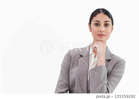 Standing in studio, woman wearing gray blazer over white blouse resting chin on hand, copy space 135359292