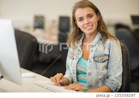 Woman typing on white keyboard at computer lab desk with desktop monitor and mouse, copy space 135359297