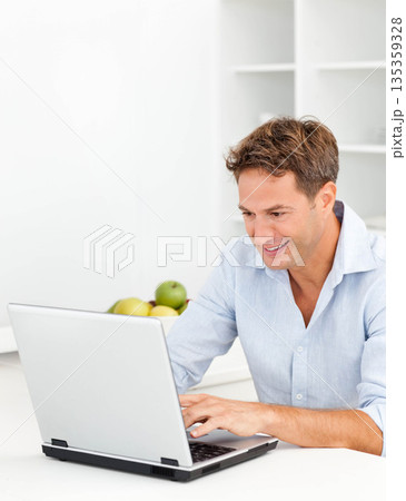 Mid adult man in shirt typing on laptop smiling at kitchen table with bowl of apples Mid adult man in shirt typing on laptop smiling at kitchen table with bowl of apples 135359328