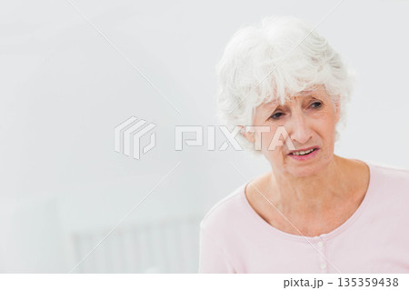 Senior woman sitting near wall-mounted radiator in bright room, wearing light pink top, copy space Senior woman sitting near wall-mounted radiator in bright room, wearing light pink top, copy space 135359438