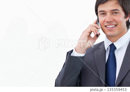 Businessman gray suit blue tie holding smartphone to ear smiling against white backdrop, copy space Businessman gray suit blue tie holding smartphone to ear smiling against white backdrop, copy space 135359453