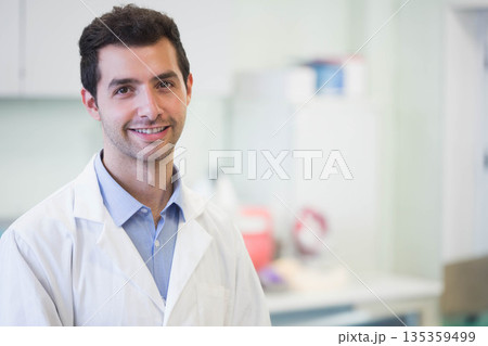 Male researcher wearing white lab coat standing in research laboratory with sharps container 135359499