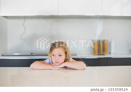 Female child leaning on quartz counter in kitchen, viewing cereal canisters beside stovetop cable Female child leaning on quartz counter in kitchen, viewing cereal canisters beside stovetop cable 135359524