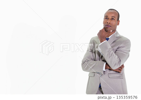African American man wearing suit and tie standing thoughtfully on white backdrop, copy space African American man wearing suit and tie standing thoughtfully on white backdrop, copy space 135359576