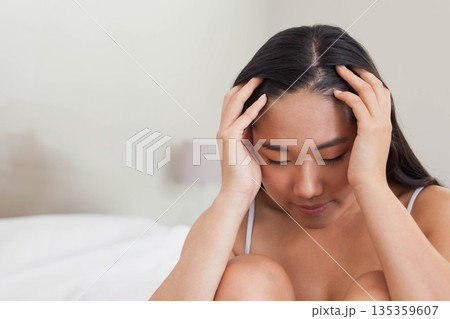 Korean woman sitting on bed pressing temples in dimly lit bedroom with bedside lamp, copy space Korean woman sitting on bed pressing temples in dimly lit bedroom with bedside lamp, copy space 135359607