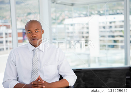 African American man sitting at desk in office facing skyline wearing white shirt, tie with laptop 135359685