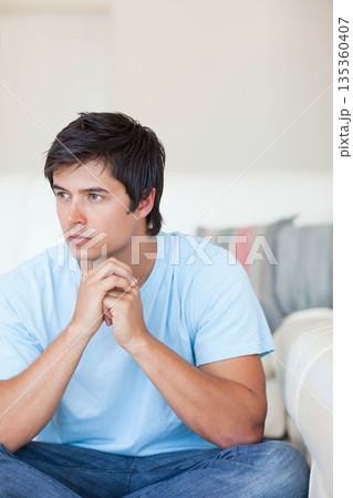 White man leaning on light-colored sofa in living room with pillow, gazing right copy space White man leaning on light-colored sofa in living room with pillow, gazing right copy space 135360407
