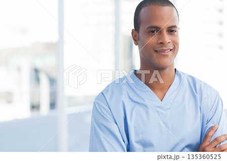 African American man in blue scrubs standing on hospital balcony overlooking skyline, copy space 135360525