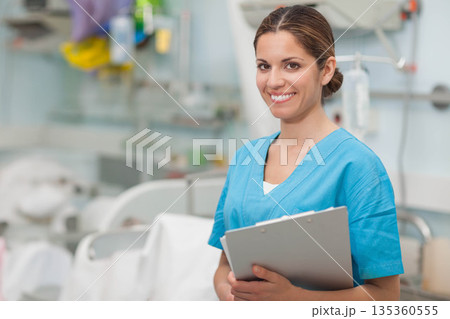 Female nurse holding clipboard while standing in hospital ward with IV stand and beds, copy space Female nurse holding clipboard while standing in hospital ward with IV stand and beds, copy space 135360555