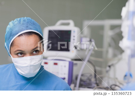 Female surgical nurse monitoring vital signs on monitor with cables in operating room, copy space Female surgical nurse monitoring vital signs on monitor with cables in operating room, copy space 135360723